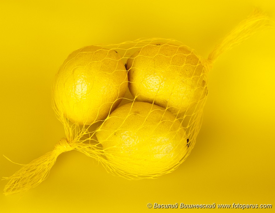 Citrus_limon_2010_0202_1554.jpg - Фрукты сфотографированные на желтом фоне. Three yellow Lemons in a string-bag on a yellow background.